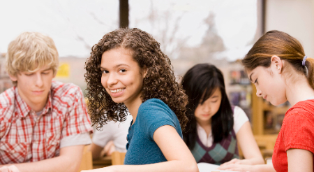 students sitting and reading one smiling facing camera 